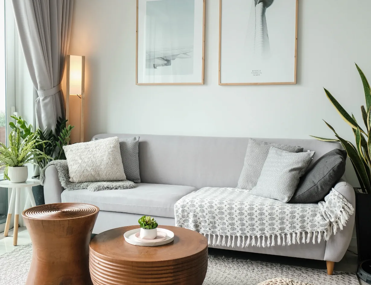 Modernes, gemütliches Wohnzimmer mit grauem Sofa, Holztisch und grünen Zimmerpflanzen, perfekt gereinigt.